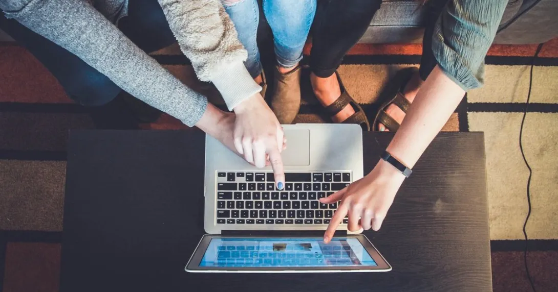 Young people pointing fingers at a laptop