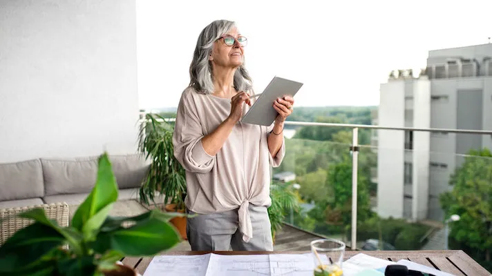 older woman on her apartment balcony with a tablet