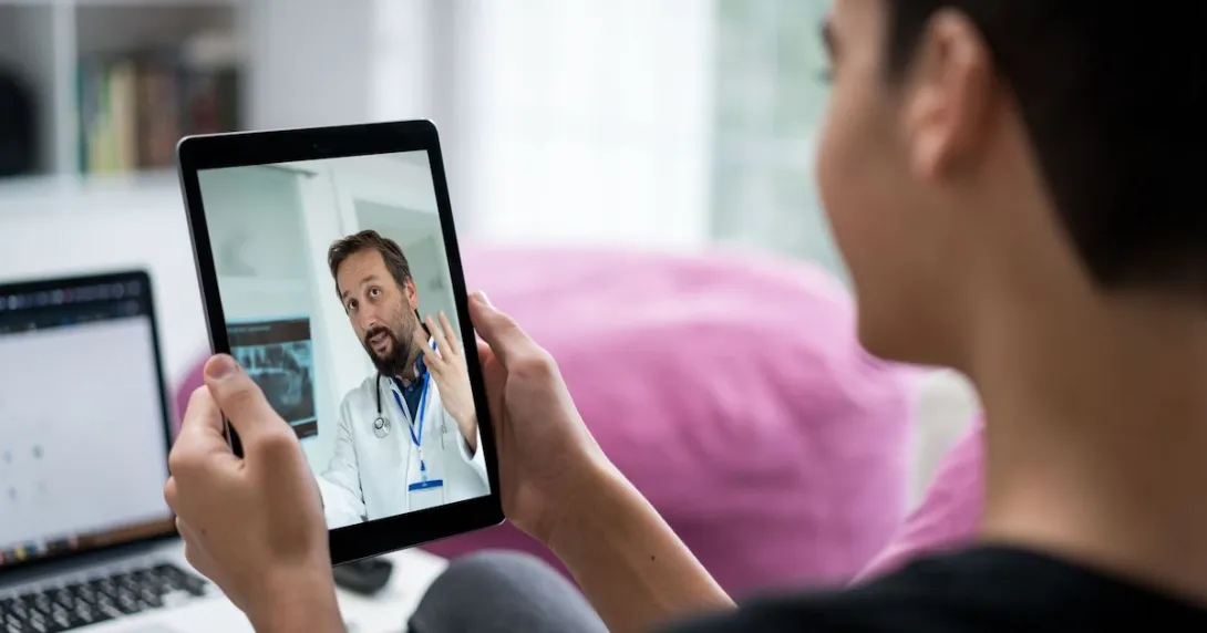 Person holding a tablet while talking to a telehealth provider