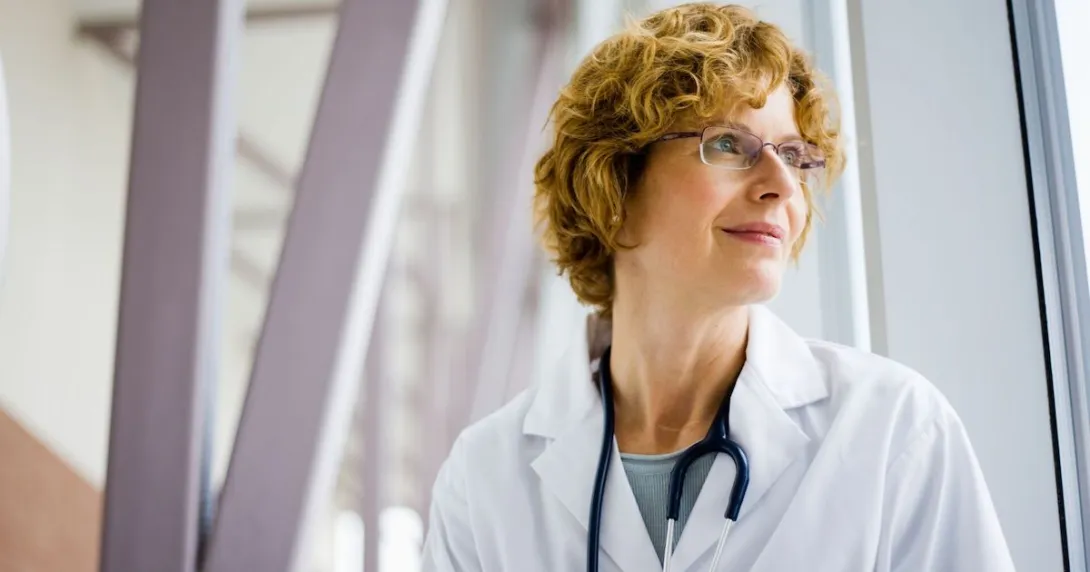 Healthcare provider wearing a stethoscope and looking out a window