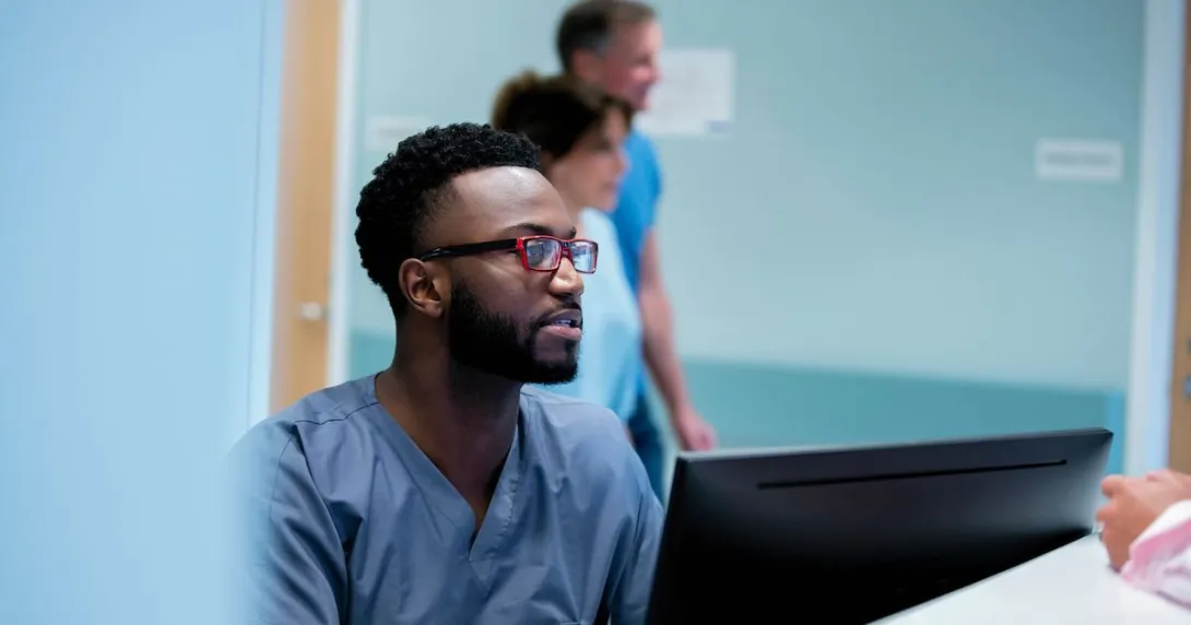 Healthcare provider in scrubs sitting at a computer