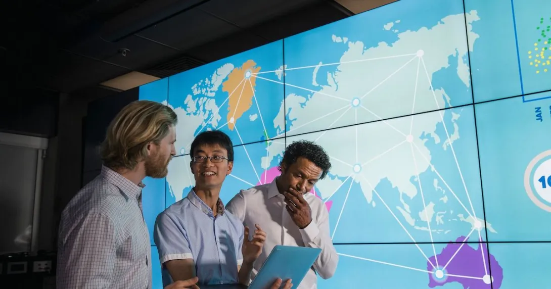 Three people standing in front of a world map