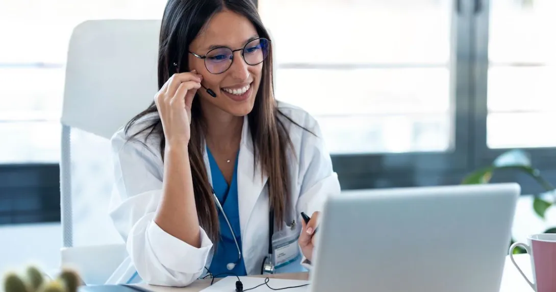 Healthcare stakeholder sitting at a desk looking at a computer with a headset on