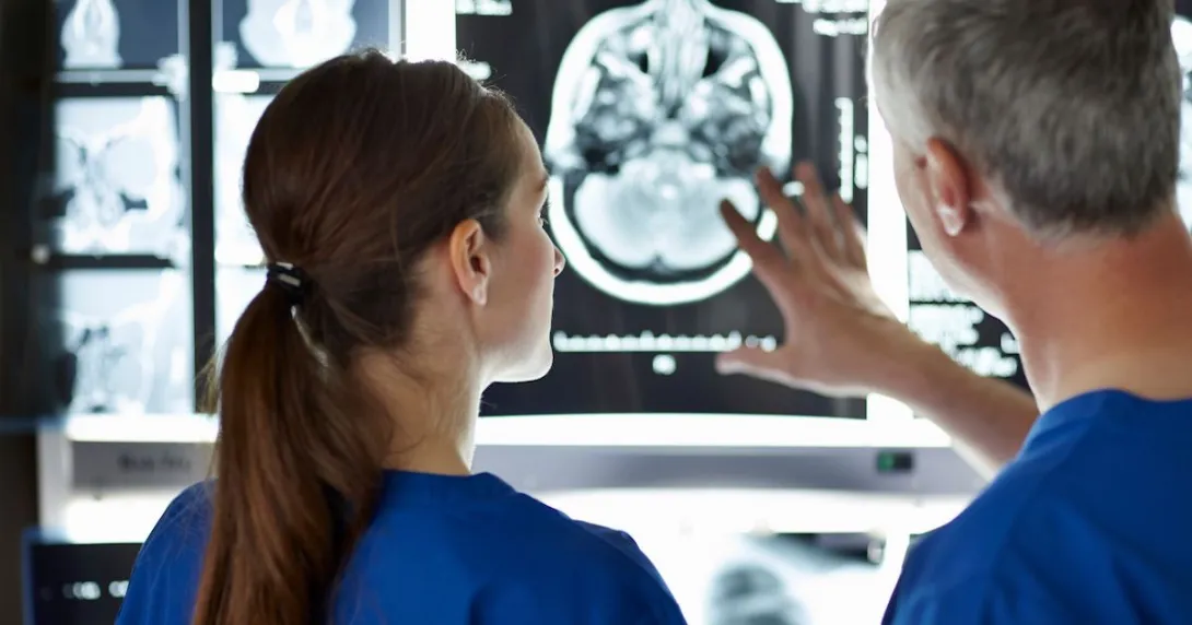 Two healthcare providers looking at a brain imaging scan