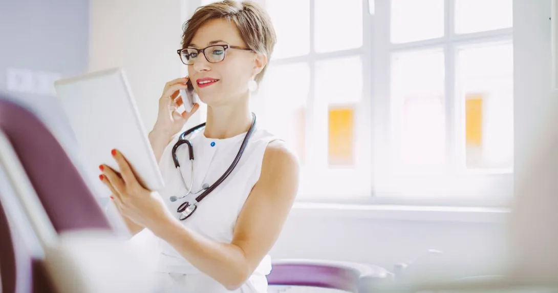 Healthcare provider wearing a white shirt and looking at a tablet