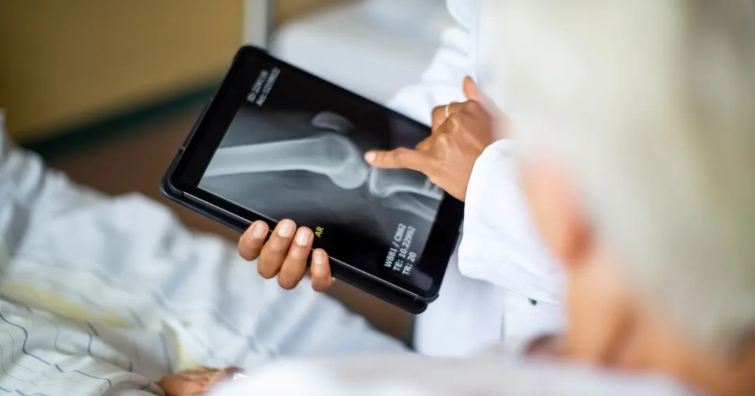 A doctor holding a digital tablet showing a patient their bone X-ray