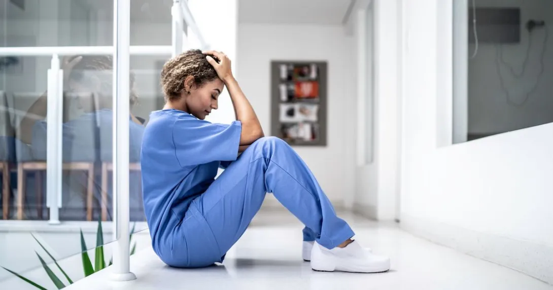 A tired nurse sitting on the floor