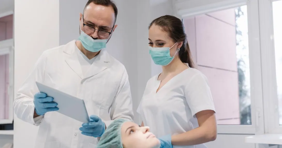 A dentist and their assistant checking a patient's record from a digital tablet